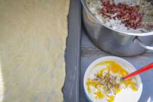 ausgerollter Hefeteig, gedünstete Zwiebeln, Eiercreme