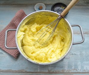 Kartoffelbrei mit Milch und Butter zu luftigem Kartoffelpüree schlagen