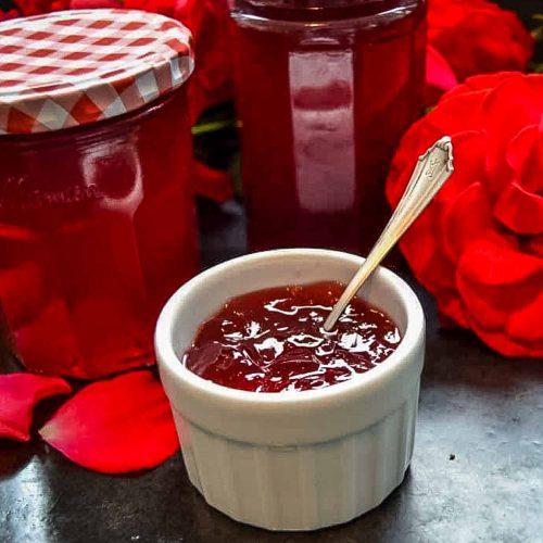 Rosengelee, Rosenmarmelade im Marmeladenglas und abgefüllt in weißem Porzellanschälchen mit Löffel