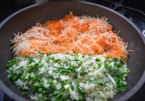 geraspelte Möhren, Zwiebel und Petersilie dünsten