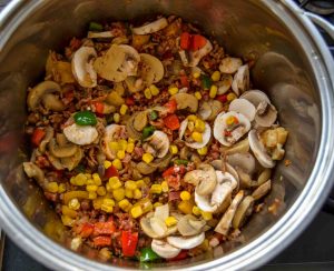 Hackfleisch, Zwiebel, Paprika und Pilze anbraten.