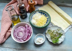 Zutaten Blätterteig, rote Zwiebel, geriebener Käse, Thymian, Olivenöl, Honig, Balsamico, Salz und Pfeffer