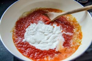 Kokosmilch, mit Tomaten und Zwiebeln dünsten