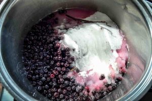Aroniabeeren im Topf mit Zucker und Wasser kochen