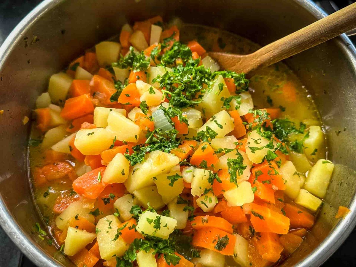 Omas Möhreneintopf im Topf vor dem Stampfen mit Kartoffeln und frischer Petersilie