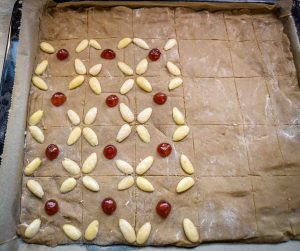 Den Pfefferkuchenteig mit Mandeln und Beleg-Kirschen belegen
