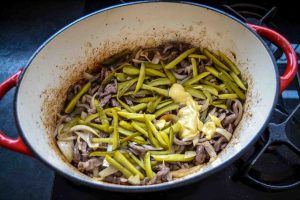 Rindfleischstreifen mit Zwiebeln und Gurkenstreifen anbraten