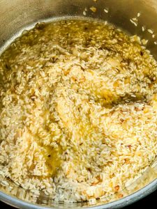 Reis in einem breiten Topf mit Schalotten Würfeln in Olivenöl unter rühren braten