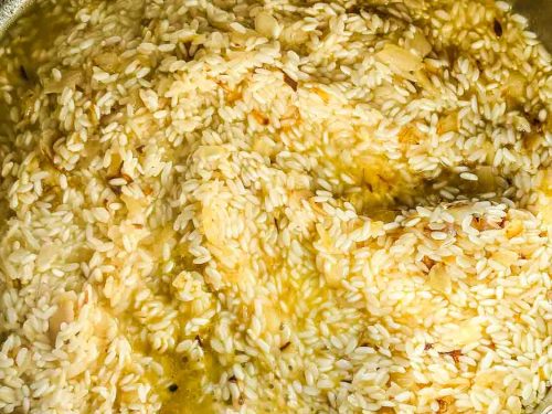 Reis in einem breiten Topf mit Schalotten Würfeln in Olivenöl unter rühren braten