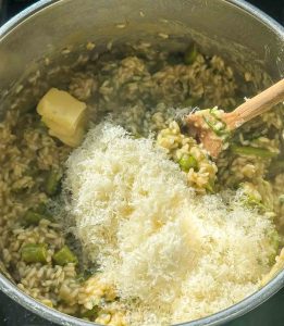 gerieben Parmesan und Butterstücke in den gekochten Risottoreis einrühren