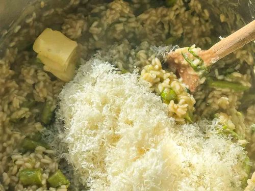 gerieben Parmesan und Butterstücke in den gekochten Risottoreis einrühren