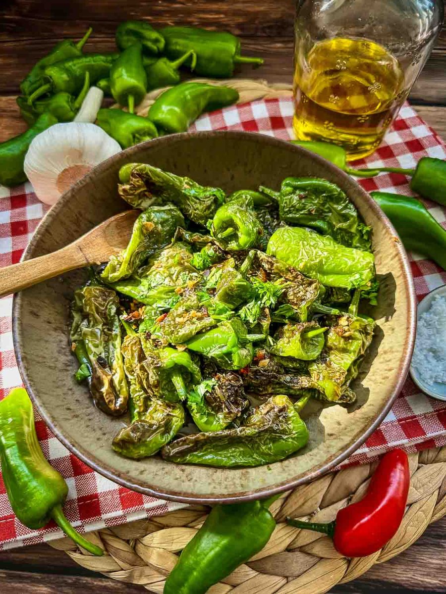 Mit Knoblauch gebratene spanische Bratpaprika in Tonschale als Tapas angerichtet 