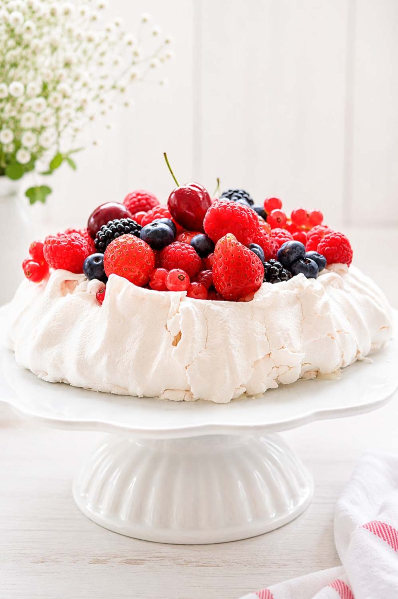 Pavlova Torte gefüllt mit Mascarpone, Sahne und bunten Beerenfrüchten