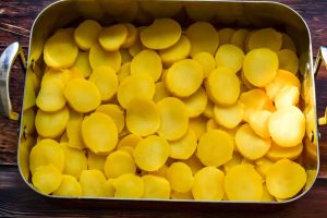 die Kartoffelscheiben in die Auflaufform legen