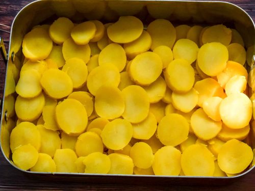 die Kartoffelscheiben in die Auflaufform legen