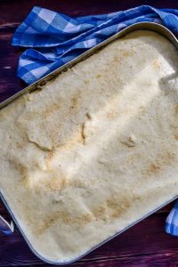 Bechamelsoße auf den griechischen Auflauf mit Kartoffeln und Hackfleisch gießen