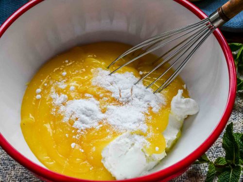 Zitronenpudding mit Quark in Rührschüssel mit dem Schneebesen verrühren