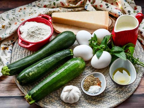 Zutaten Zucchiniquiche, Eier, Parmesan, Minze, Mehl, Sahne, Gewürze und Zucchini