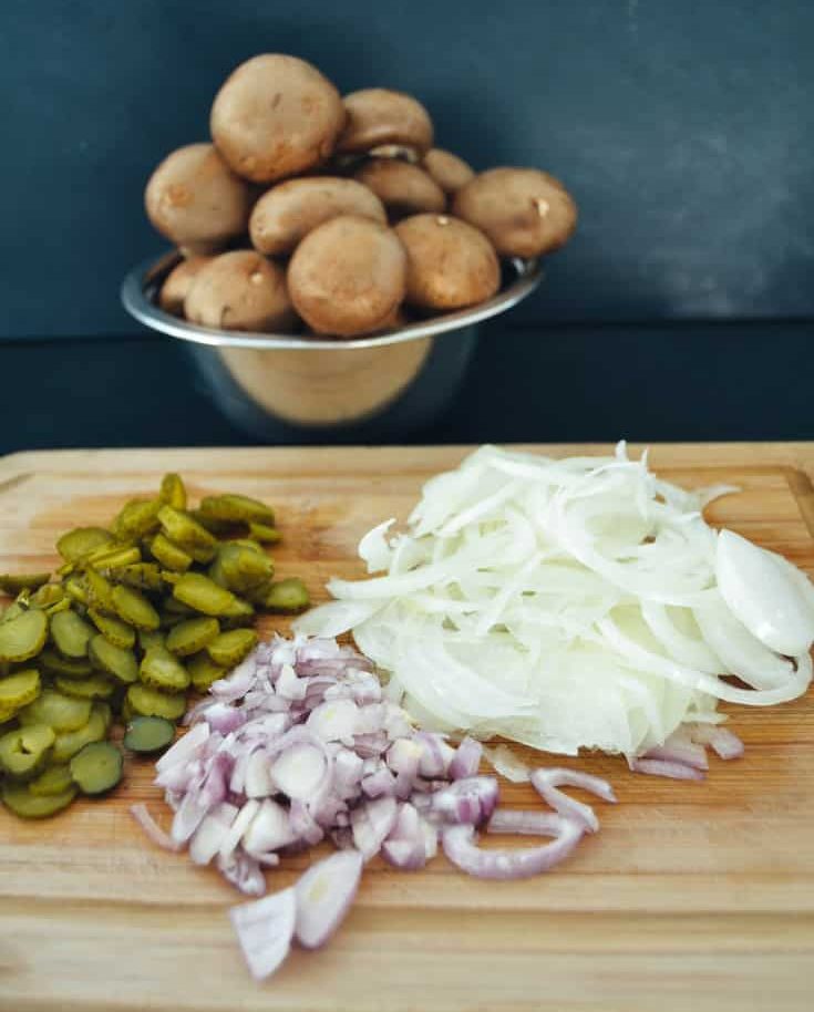 Zutaten für ein Boeuf Stroganoff Rezept Pilze, Gurkenscheiben, Schalotten und Zwiebelringe